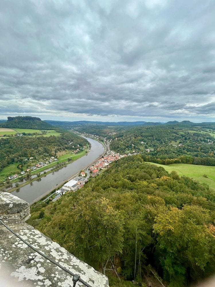 Der weite Blick von der Festung Königstein auf die Elbe. Ein Stück Mauer. Wald. Grün. Viele Wolken. (C) Herr Montag